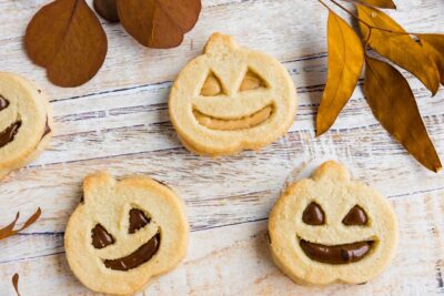 three pumpkin sandwich cookies with dries leaves above