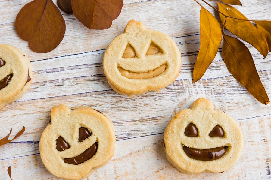 three pumpkin sandwich cookies with dries leaves above