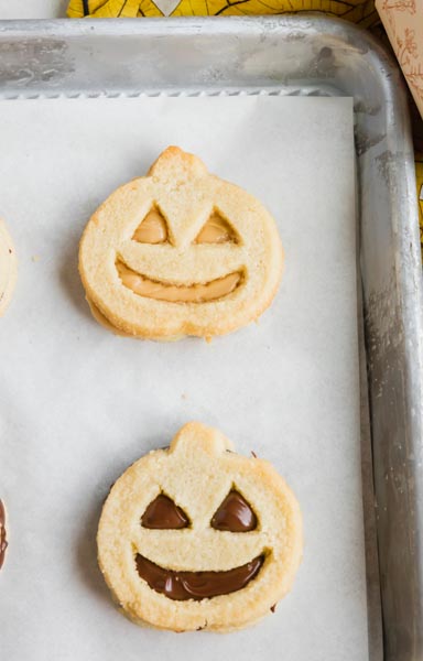two chocolate filled sandwich cookies in the shape of pumpkins on a baking tray