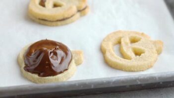 melted chocolate topped on a cookie next to a jack o lantern faced cookie