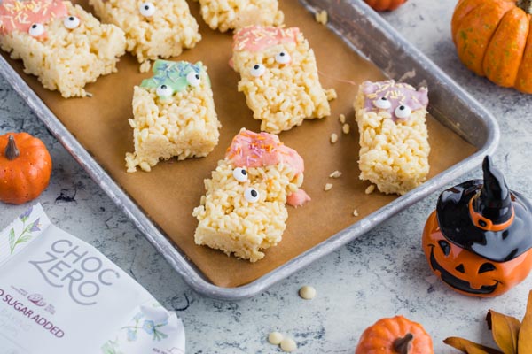 halloween decorated rice crispy treats on a tray with a jack-o-lantern