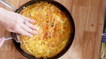 lifting a slice of frittata out of the pan with a server