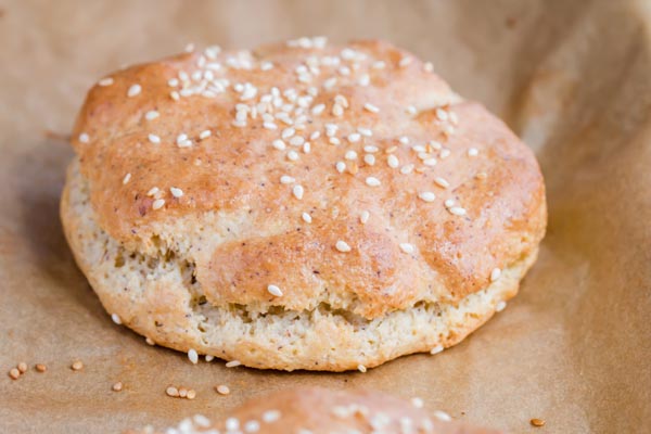 gluten free hamburger bun on a baking tray with sesame seeds on top