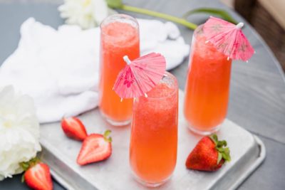 three tall glasses of keto white claw slushy on a tray with strawberries nearby