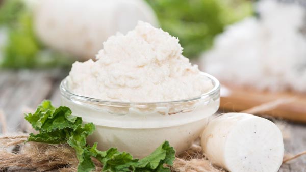 a dish full of prepared horseradish next to a whole root