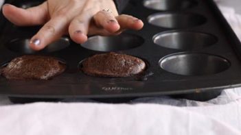 patting the top of a cupcake to make sure it is set