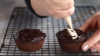 piping white icing swirl on top of a cupcake