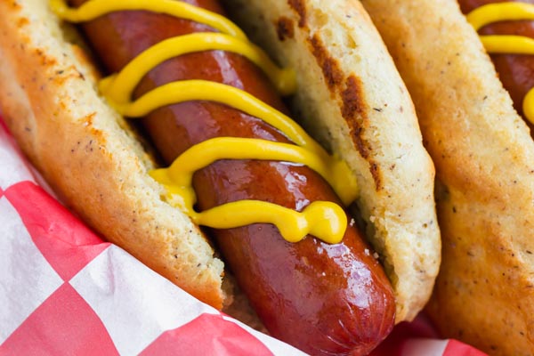 a couple of keto hot dogs in a basket topped with mustard