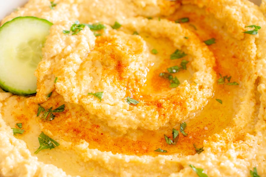 Close up of lupini hummus topped with olive oil, parsley and paprika.