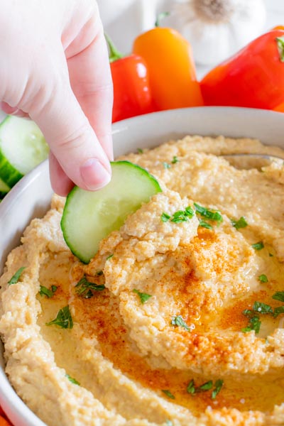 Annie from ketofocus dipping a cucumber slice into hummus.