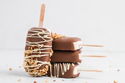 ice cream bars covered in chocolate stacked up with one covered in nuts