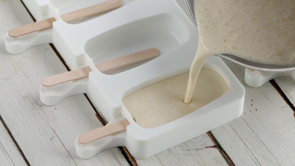 pouring vanilla keto ice cream mixture into a silcone popsicle mold