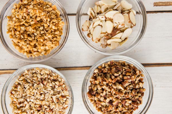 four bowls containing different crushed nuts