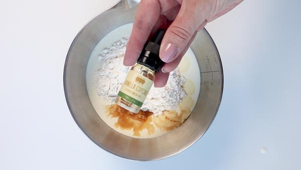 concentrated vanilla cupcake flavoring bottle over a metal bowl with ice cream mixture in it