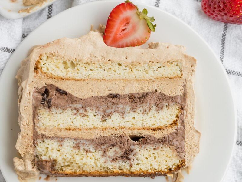 Layered ice cream cake slice with chocolate ice cream and a strawberry.