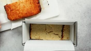 a layer of cut of pieces of cake in a rectangle loaf pan lined with parchment