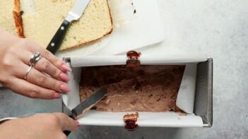 spreading chocolate ice cream in a loaf pan with sliced cake nearby