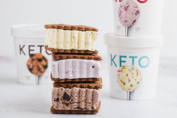 a stack of ice cream sandwiches in front of keto pint ice cream containers
