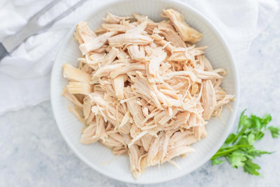 shredded chicken breast in a bowl with a meat fork nearby