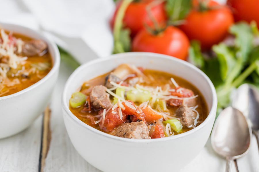 chunky beef stew with tomatos and kale in the background