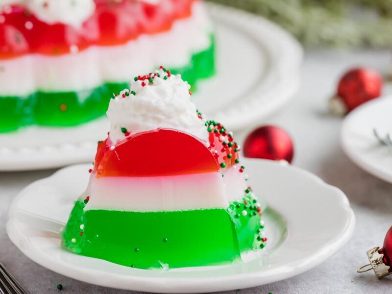 A slice of red, white and green layered jello salad on a plate.