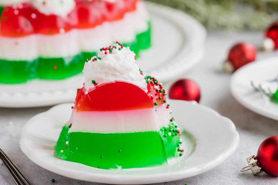 A slice of red, white and green layered jello salad on a plate.