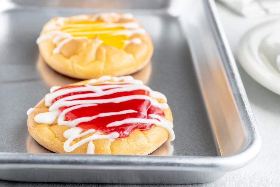 a silver baking tray with two big jelly filled danishes on top