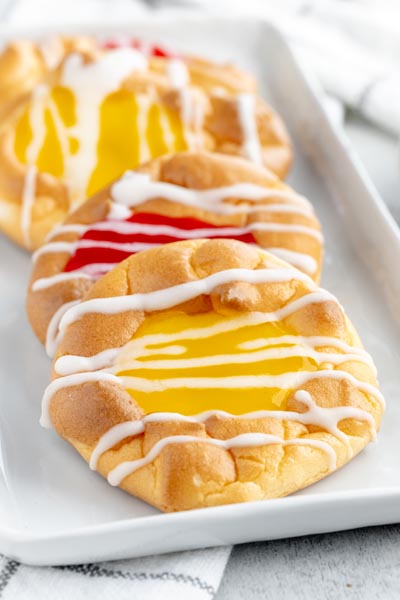 a plate with lemon and cherry filled danishes topped with icing