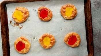 a baking tray with six danishes, alternating red and yellow filling colors