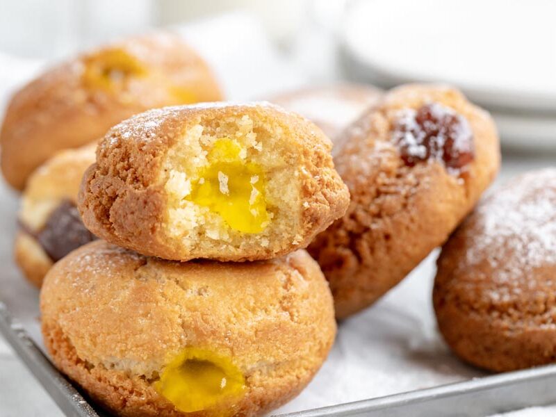two donuts on top of each other with a bite out of a lemon jelly filled donut