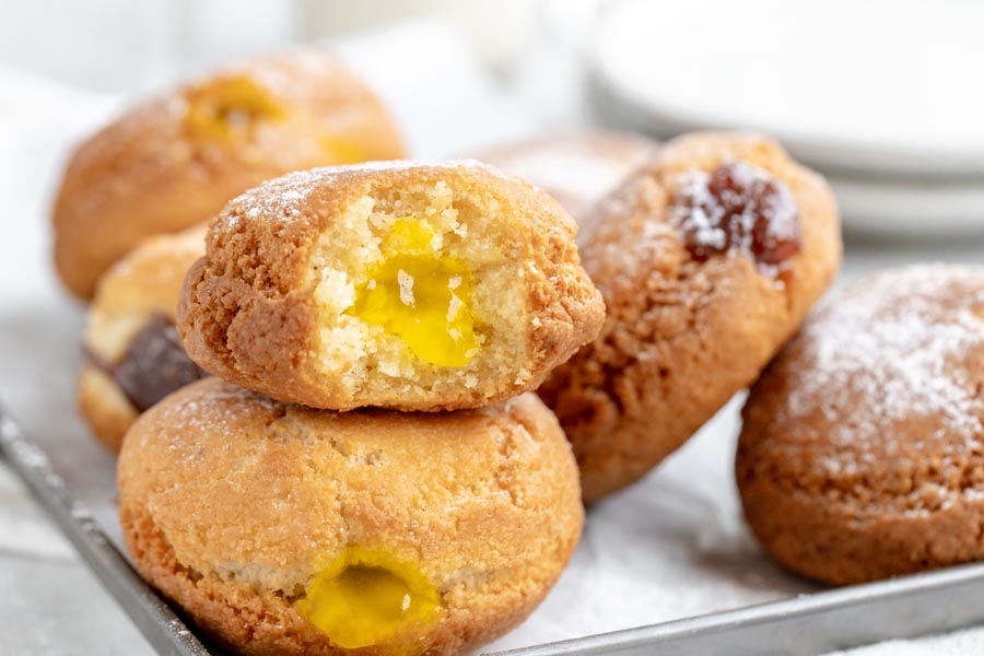 two donuts on top of each other with a bite out of a lemon jelly filled donut