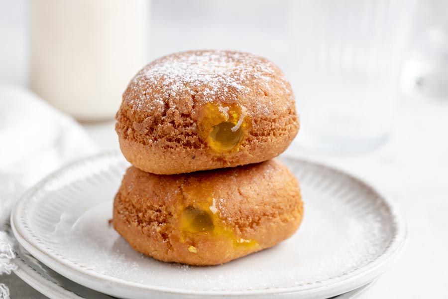 two lemon filled donuts on top of each other with the top one dusted with powdered sugar