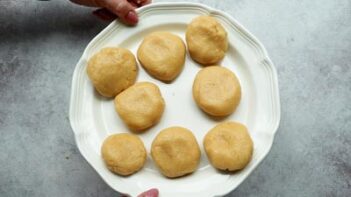 eight small bun shaped balls of dough on a white plate