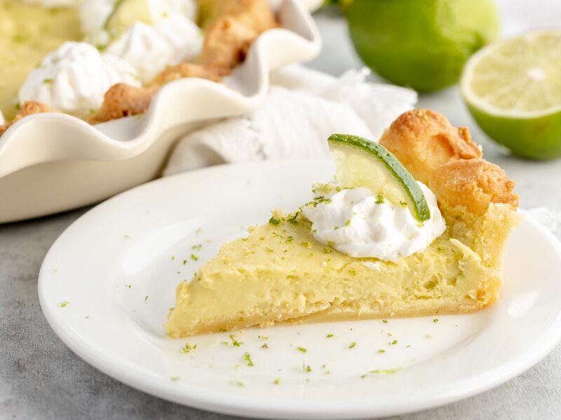 a slice of silky cream pie on a small white plate with green lime zest sprinkled around