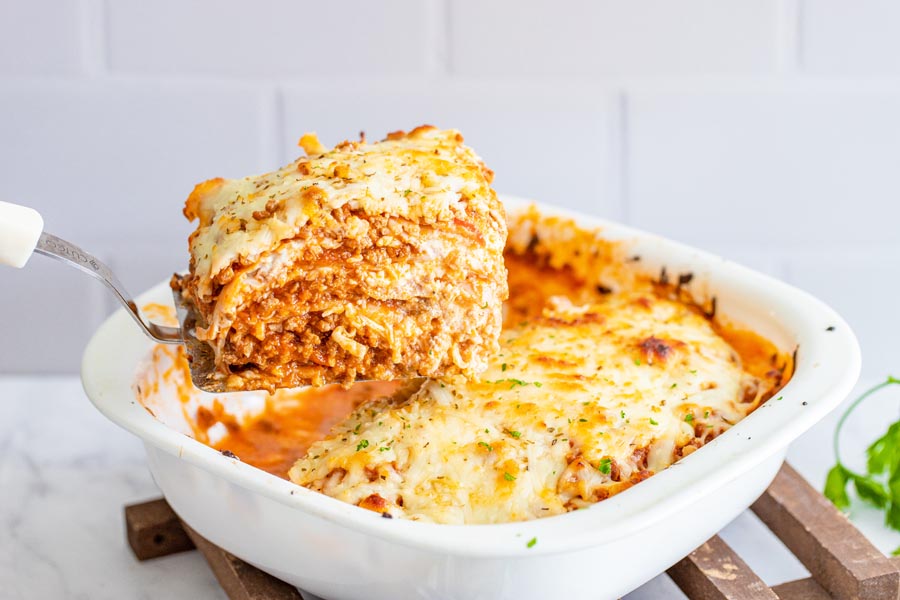 lifting a keto lasagna slice out of a pan