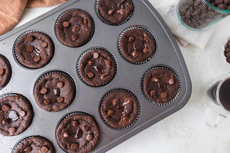 A full tray of freshly baked keto lava cake muffins topped with melted chocolate chips.