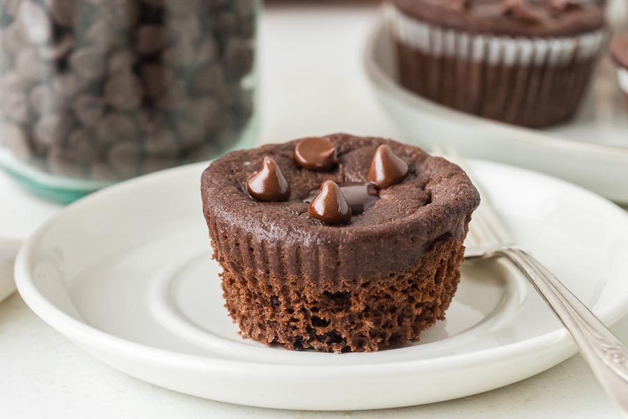 A single keto chocolate muffin topped with glossy chocolate chips, displayed on a white plate.
