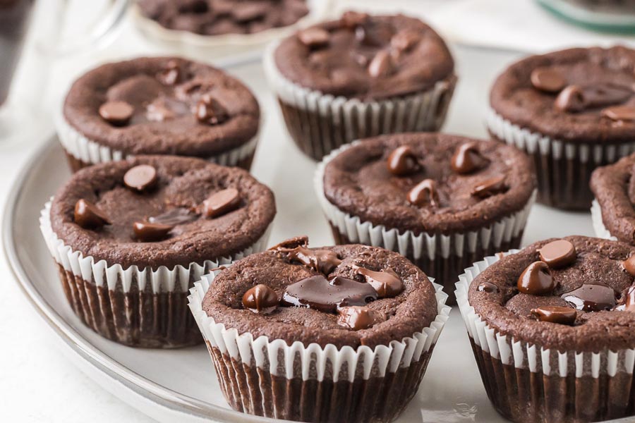 A serving platter filled with keto lava cake muffins, each topped with melty chocolate chips.