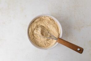 A bowl of dry ingredients with a whisk, showing the almond flour and protein powder mixture.