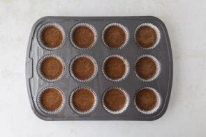 Muffin pan with liners now filled halfway with chocolate batter, ready for baking.