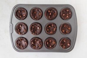 Fully baked lava cake muffins in the tin, topped with melted and whole chocolate chips.