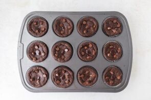 Baked lava cake muffins in the tin, showing rich chocolate tops and slightly melted centers.