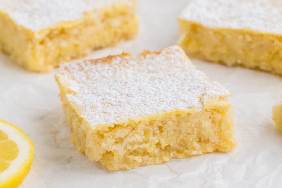 A small lemon square in front of two lemon squares.