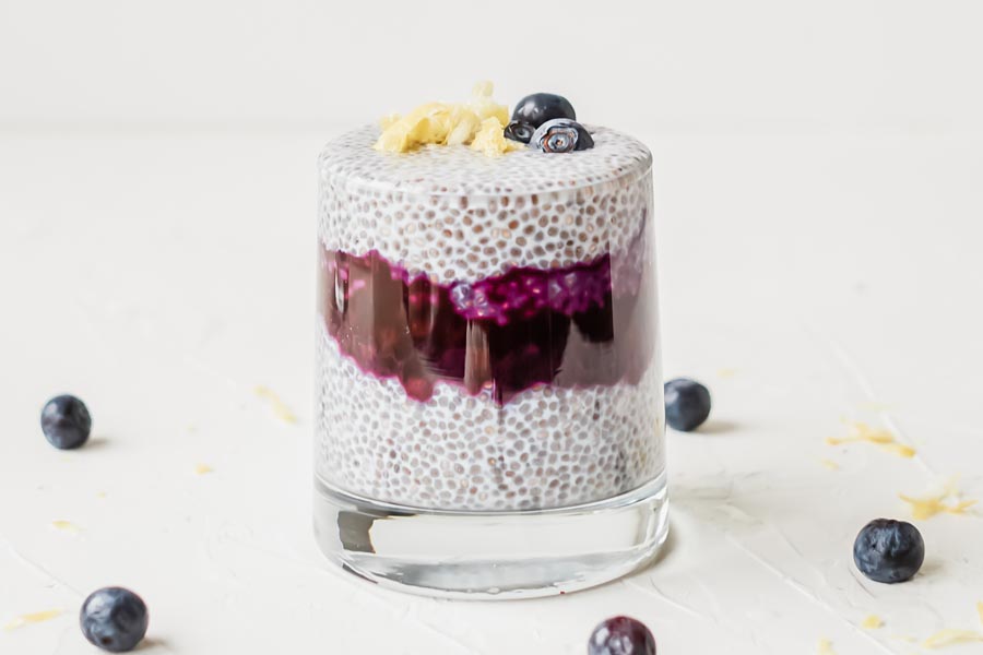 a glass of chia pudding with blueberry syrup and lemon zest on top
