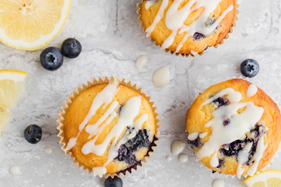 overhead view of blueberry muffins topped with glaze and lemon slices nearby