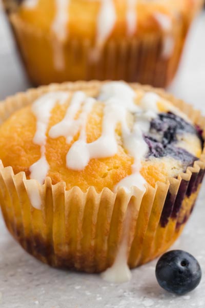 A closeup of a blueberry muffin topped with a white glaze drizzle.