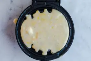 pouring lemon chaffle on waffle maker