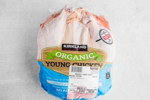 a whole organic chicken on a white counter still in the packaging