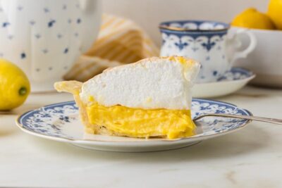 Slice of keto lemon meringue pie on a blue-and-white floral plate.
