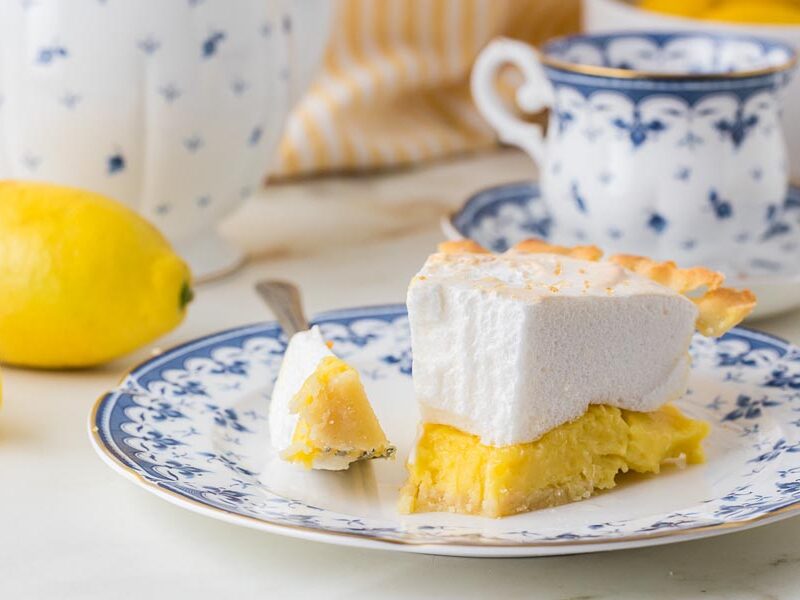 Close-up of a partially eaten slice of keto lemon meringue pie showcasing the smooth lemon filling and airy meringue topping.